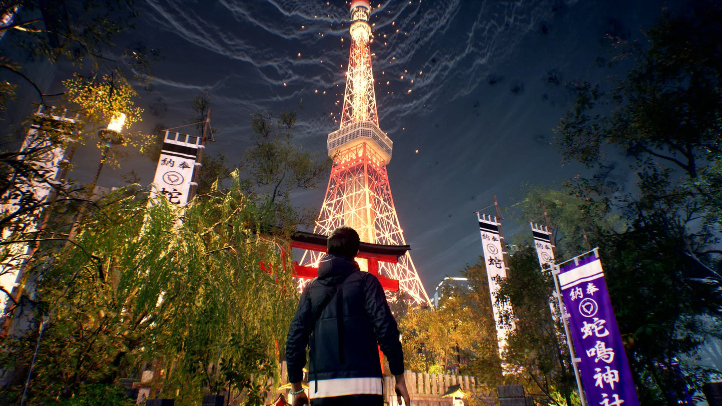 Person standing in front of Tokyo Tower at night with illuminated trees and signs.