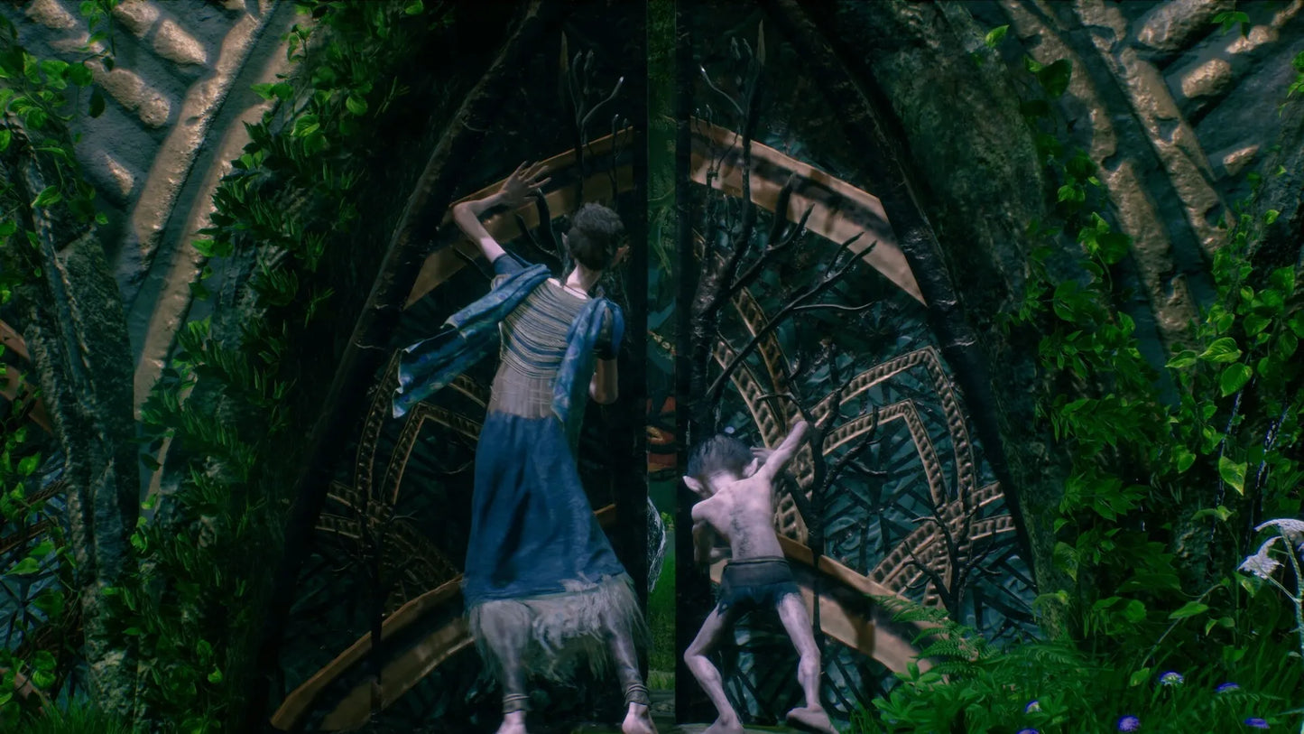 Two people standing in front of a large, ornate door with intricate designs, surrounded by greenery.