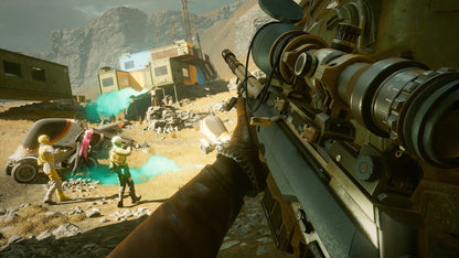 First-person view of a character holding a large weapon in a desert-like environment with structures and people in the background.