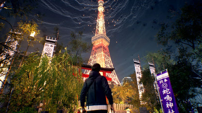 Person standing in front of Tokyo Tower at night with illuminated trees and signs.