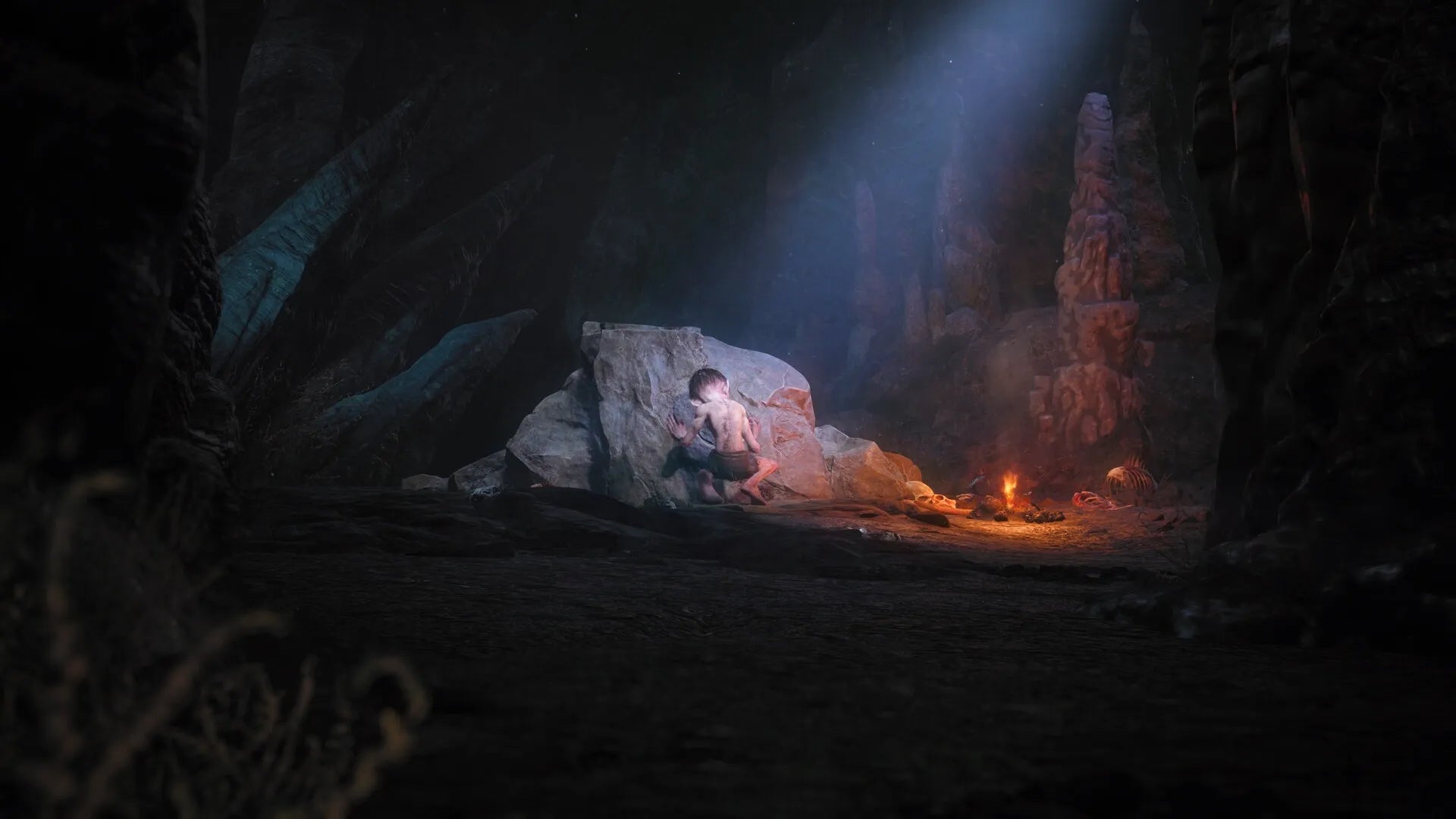 Dark cave scene with a person sitting on a rock, illuminated by a torch.