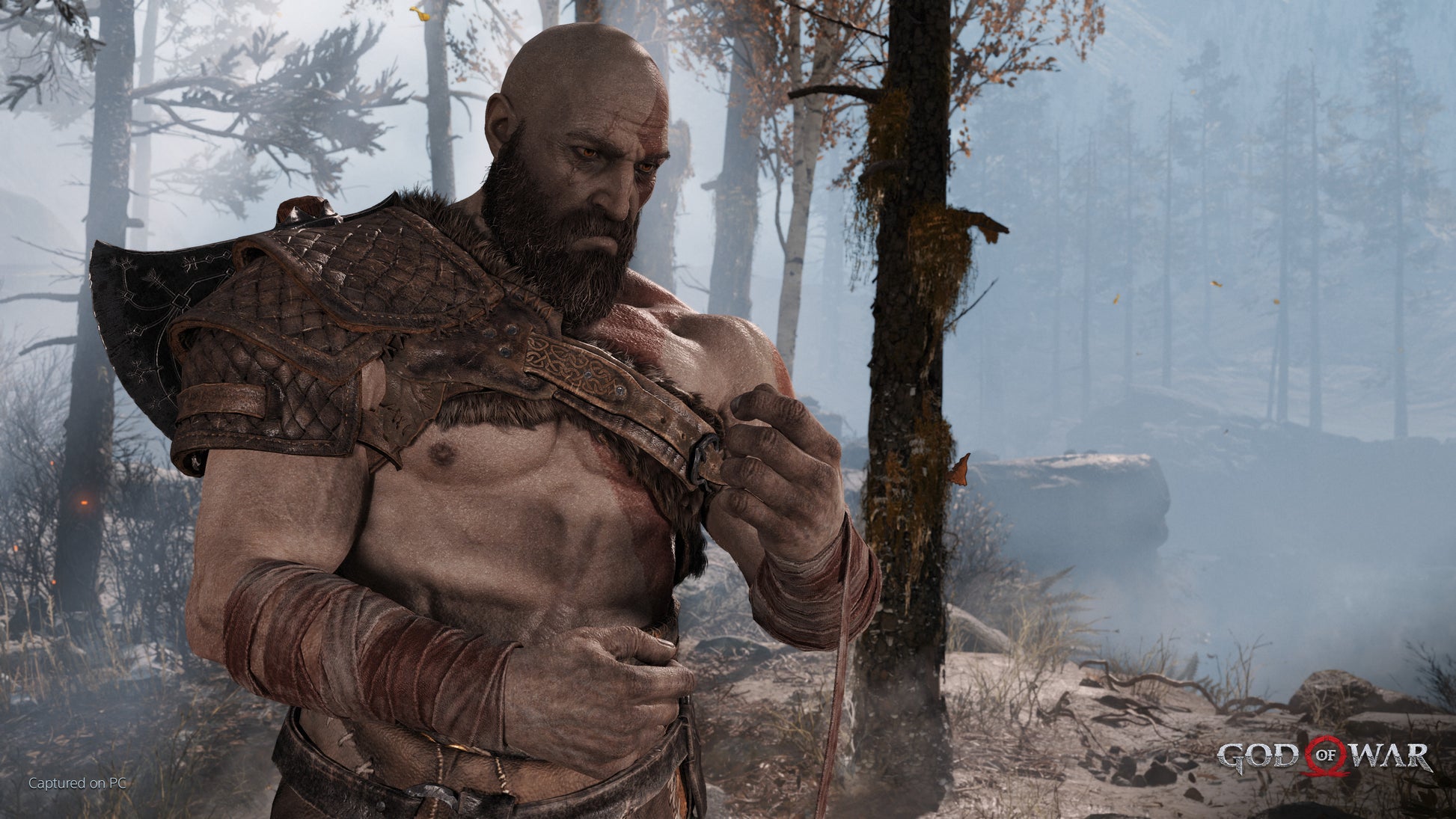 Character in warrior attire standing in a forest with 'God of War' logo.