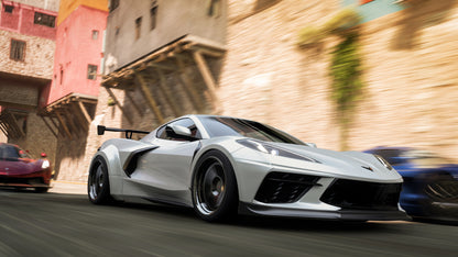 Silver sports car racing on a street with colorful buildings in the background