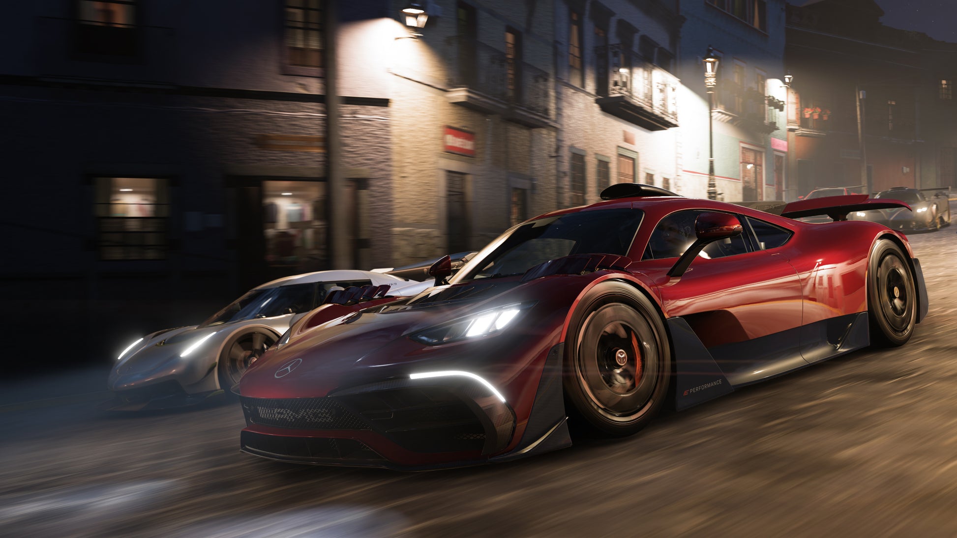 Two high-performance cars racing on a city street at night.