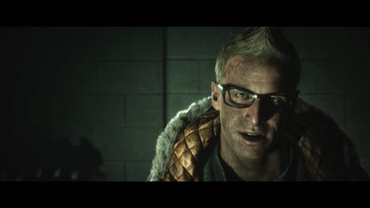 Person wearing glasses and a fur-lined coat in a dimly lit room