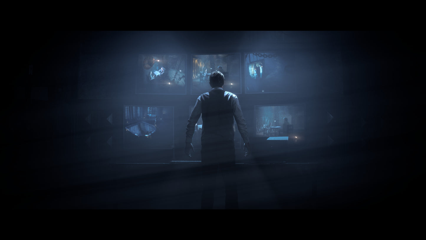 Person standing in a dark room with multiple screens displaying various images.