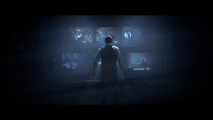 Person standing in a dark room with multiple screens displaying various images.