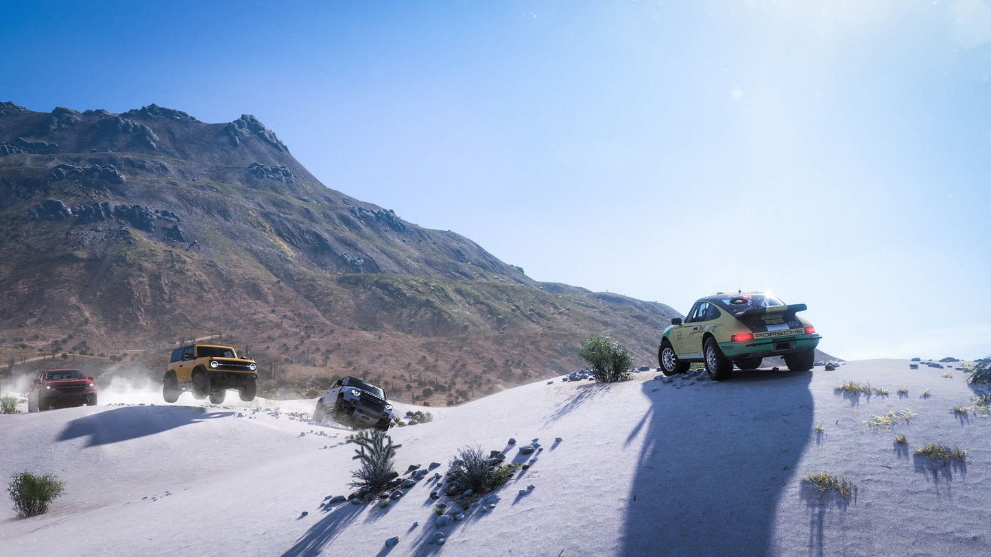Off-road vehicles on a desert road with mountains in the background