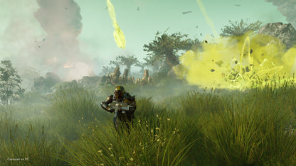 Character in a grassy field with explosions and smoke in the background