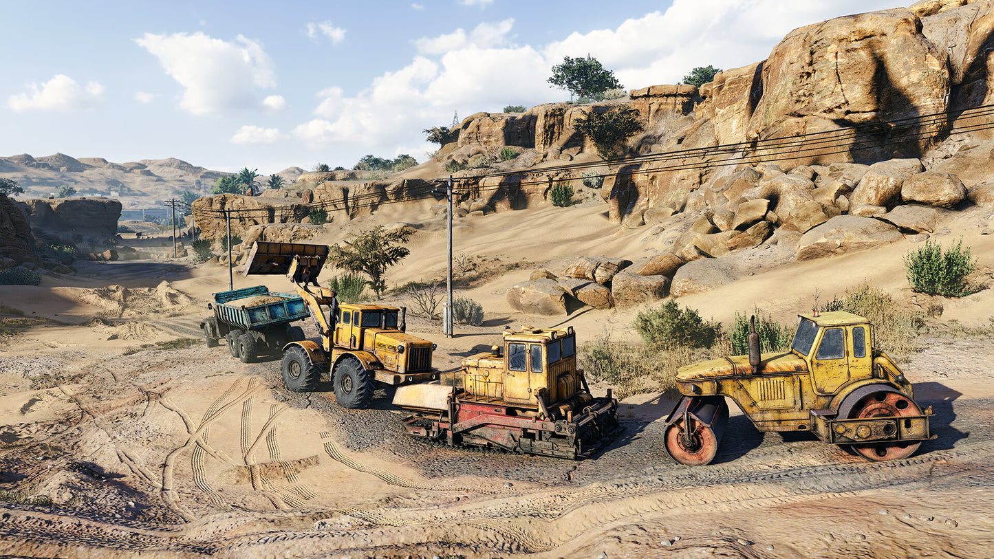 Construction vehicles on a dirt road with rocky landscape and blue sky.