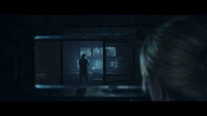 Person observing another person through a grille in a dimly lit room