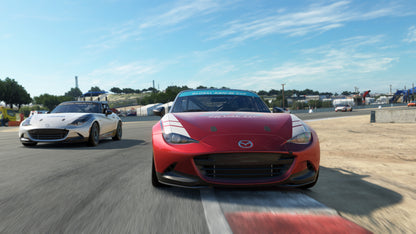 Two cars racing on a track with a clear blue sky.