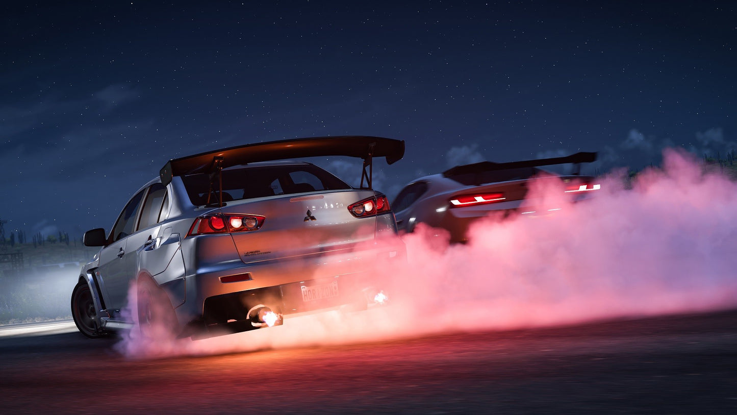 Two cars performing a drift on a road at night with smoke trailing behind them.