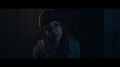 Person wearing a beanie and scarf in a dark setting