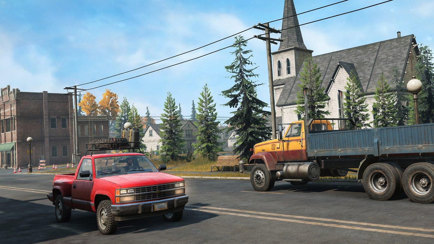 Two pickup trucks on a street with a church and trees in the background