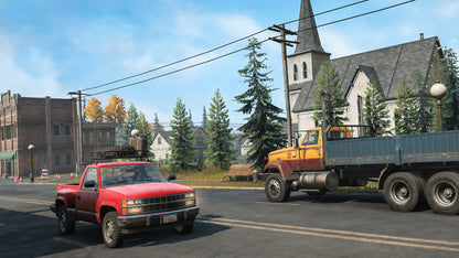 Two pickup trucks on a street with a church and trees in the background