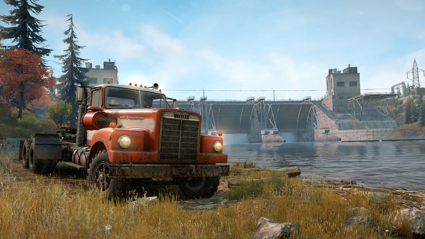 Rustic red truck near a dam with water and trees in the background
