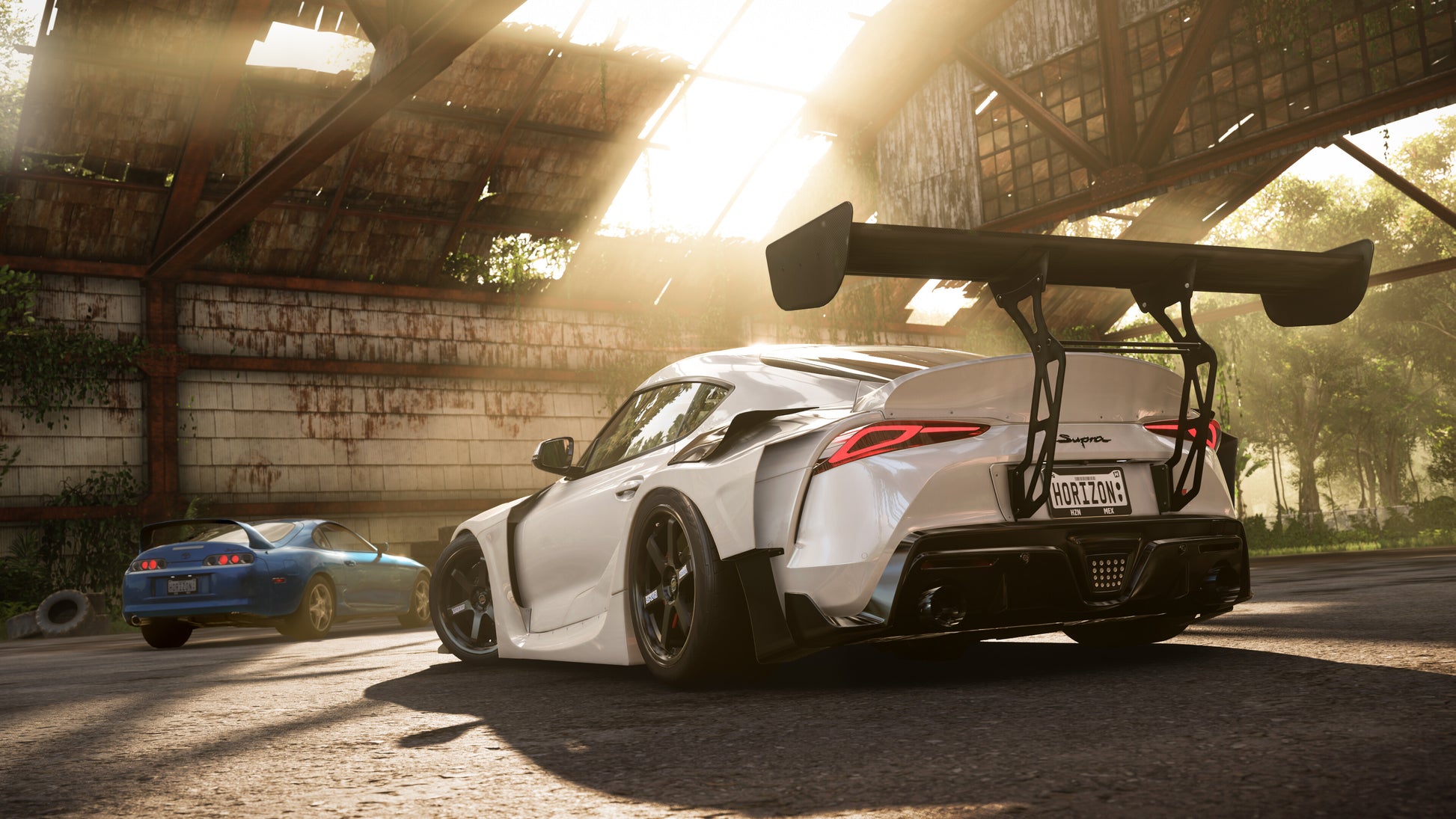 White sports car with a large rear wing in a sunlit garage