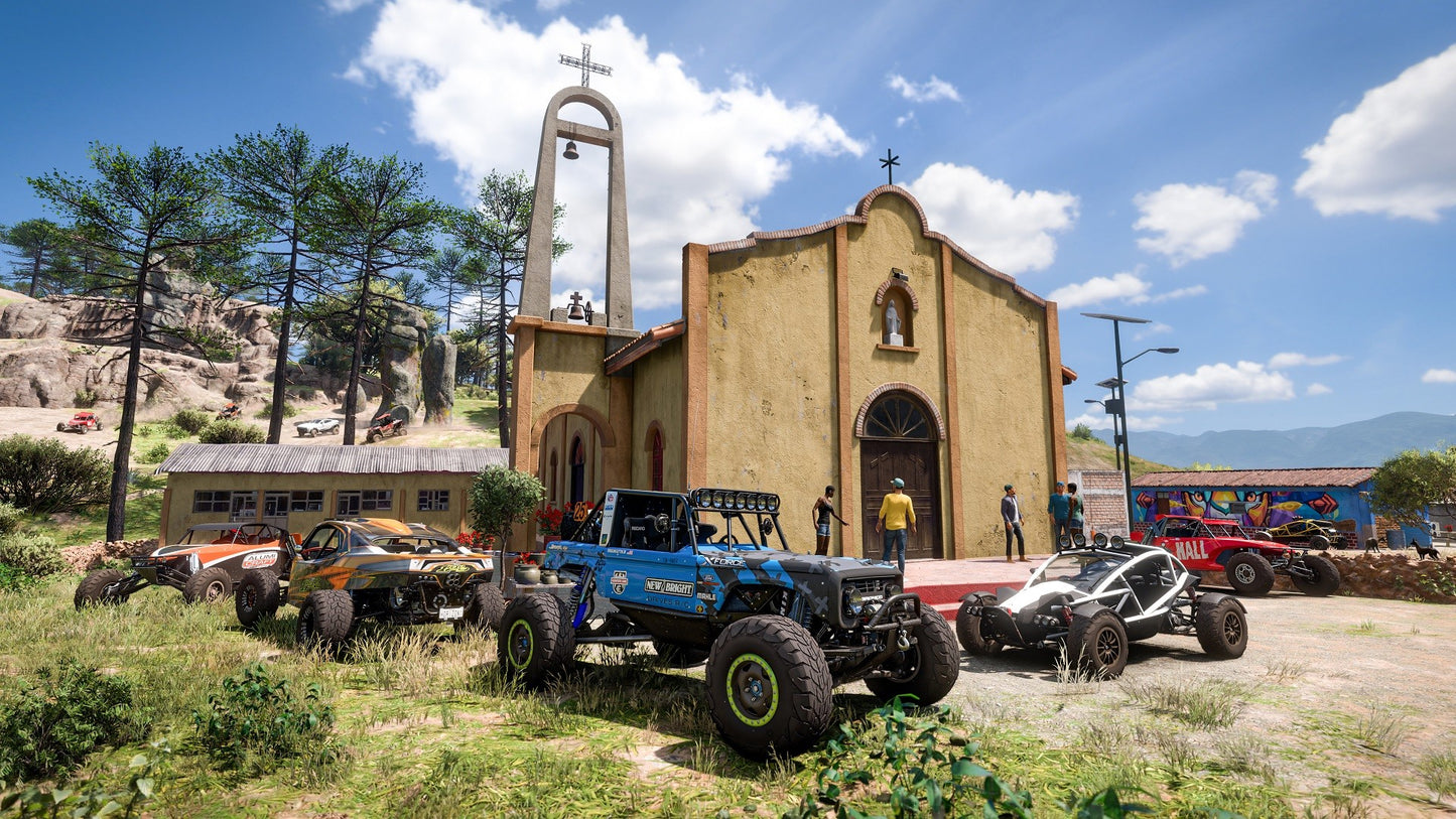 Off-road vehicles parked in front of a church with a mountainous background