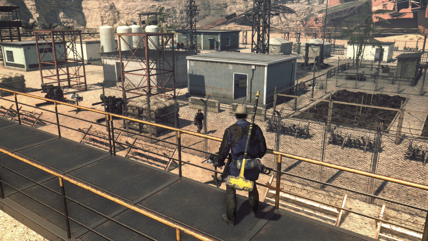 Person walking on a platform in a desert-like industrial area with buildings and equipment.
