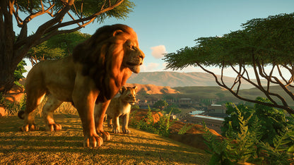 Lioness and cub walking on a dirt path with trees and mountains in the background