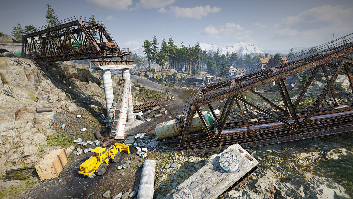 Wrecked train bridge with a yellow excavator in a forested area